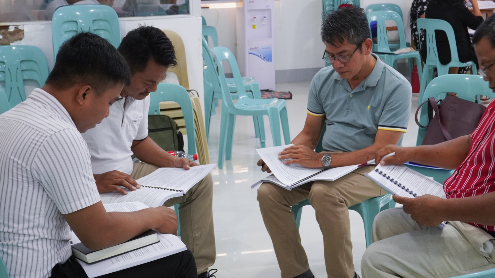 Four pastors studying spiral-bound Shepherds Global Classroom course handbooks together